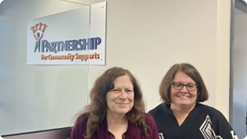 two women standing under their business sign