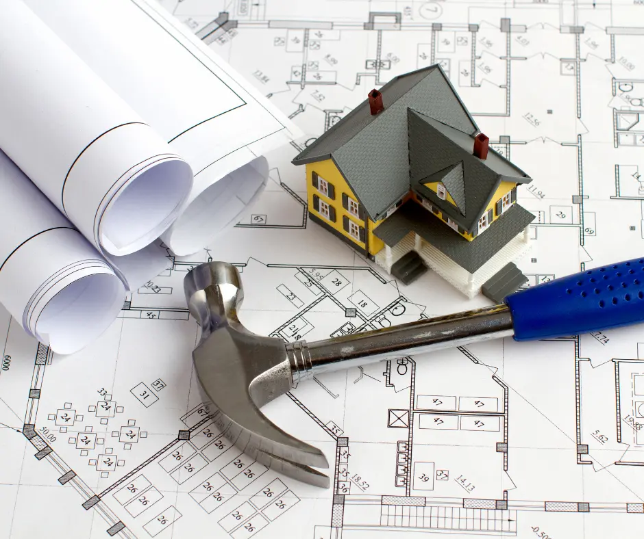 architectural models and drawings on a table with a hammer with a blue handle