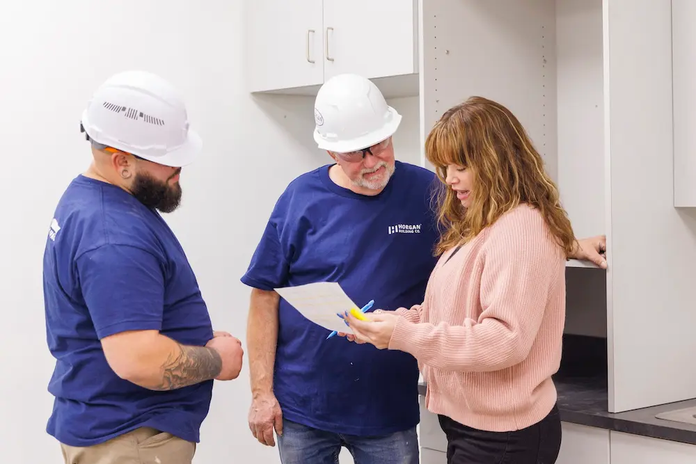 two men in hard hats standing with women reviewing plans for construction