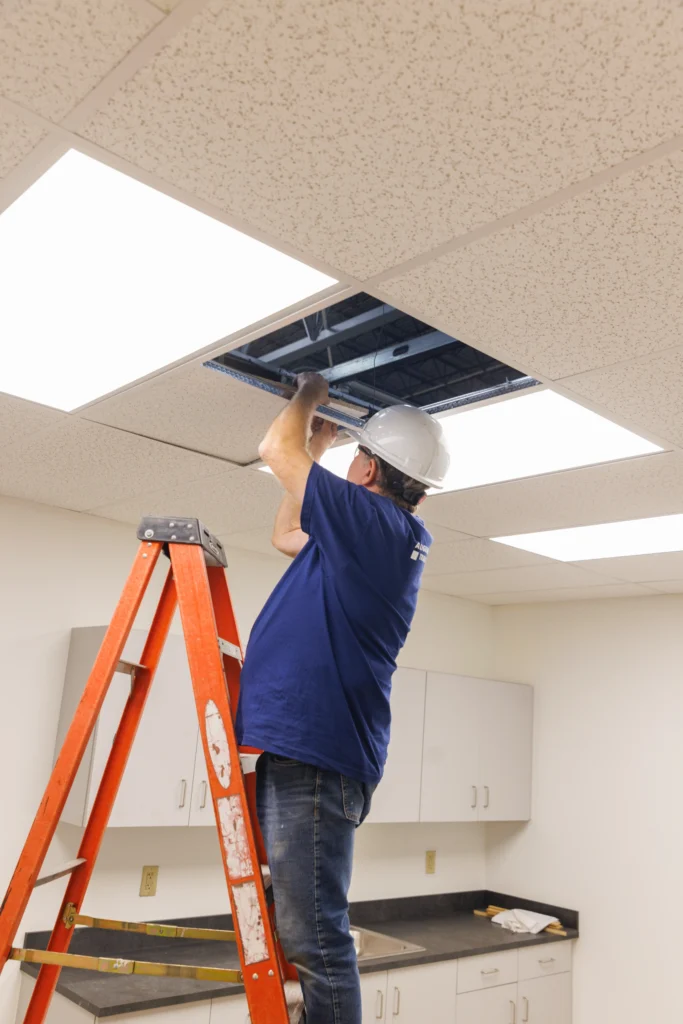 construction worker with hard hat repairing the ductwork in the ceiling