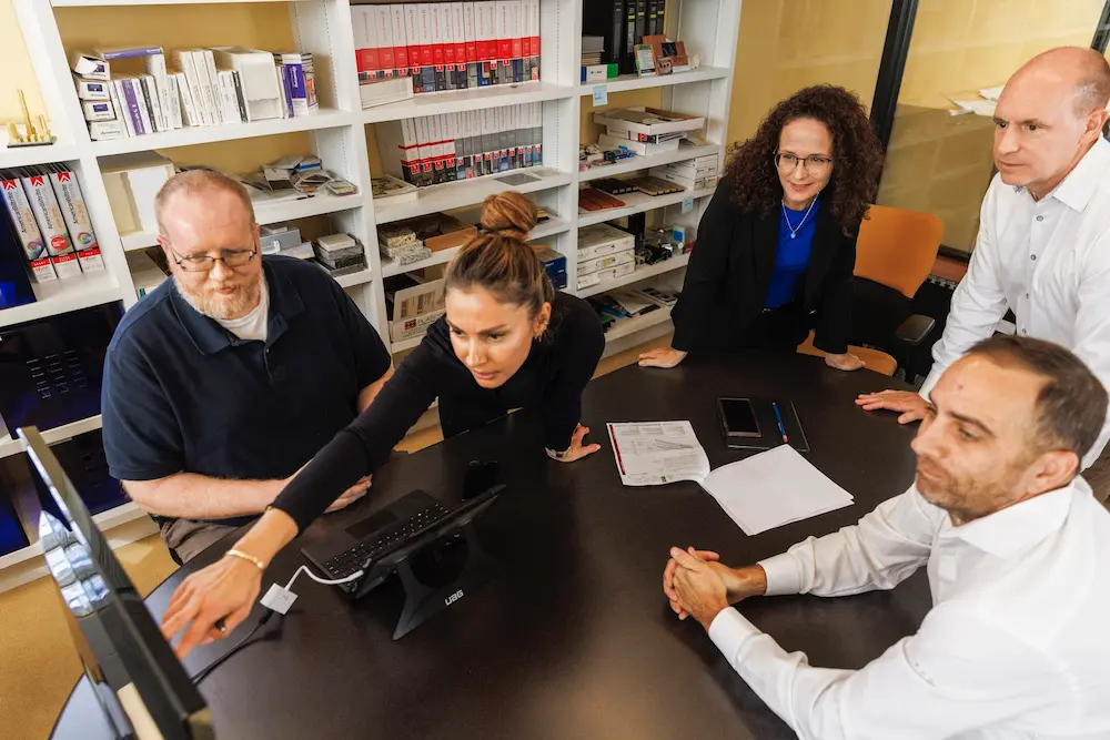 a diverse team actively reviews a plan on the monitor in a conference room