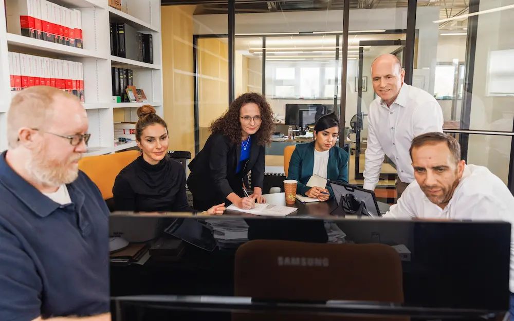 diverse group planning around computers and charts in a conference room