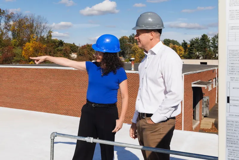 Man and Woman in hard hats surveying a construction site