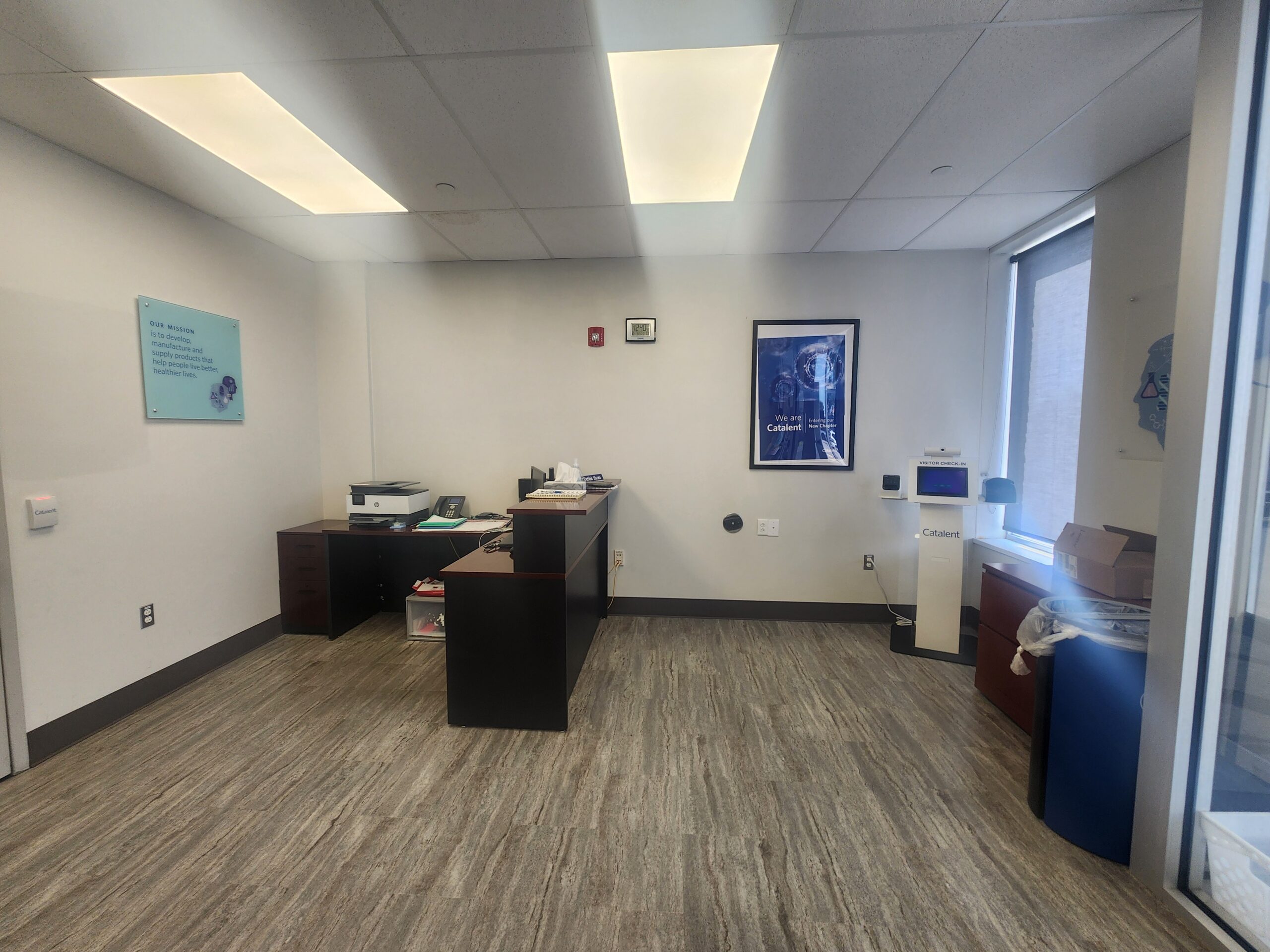 lobby area with old desk flouresecnt overhead lighting and minimal seating