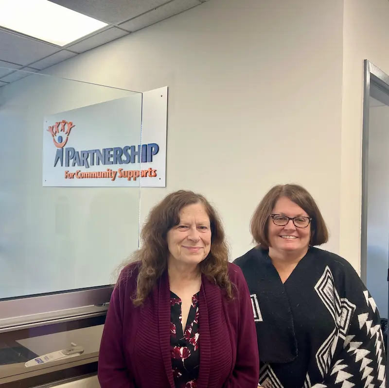 two women standing under the sign the says Partnership