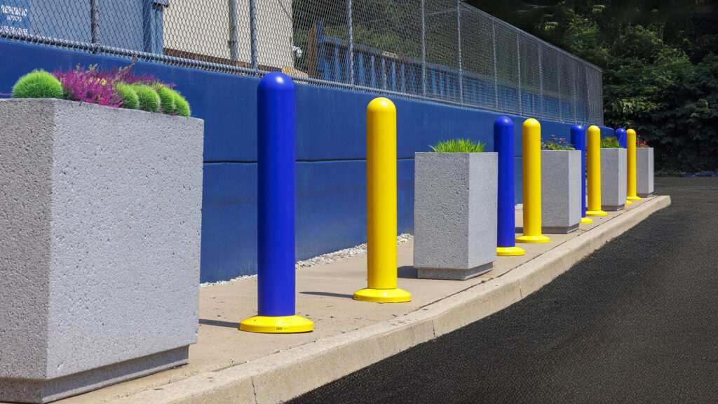 Colorful yellow and blue bollards with planters improve safety along the school’s perimeter walkway.