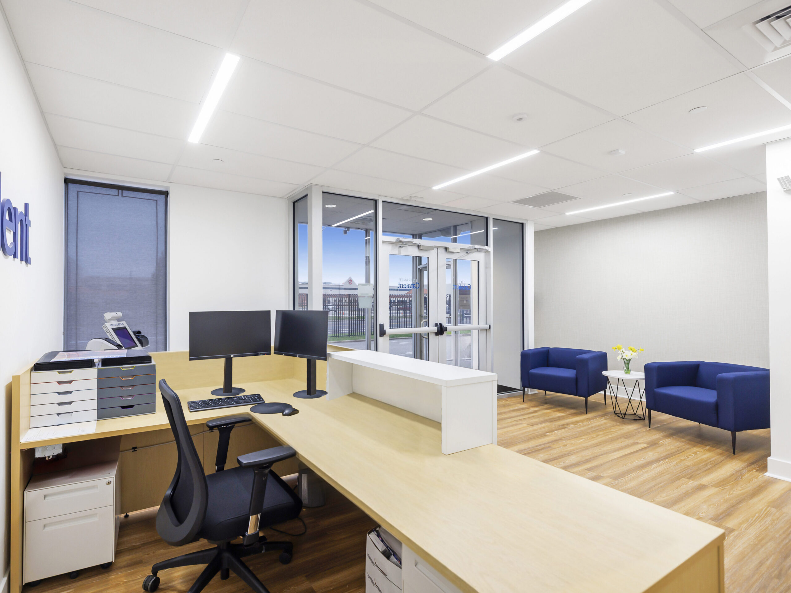 bright office area with l-shaped wood desk, modern sleek bright blue seathing and white office accessories