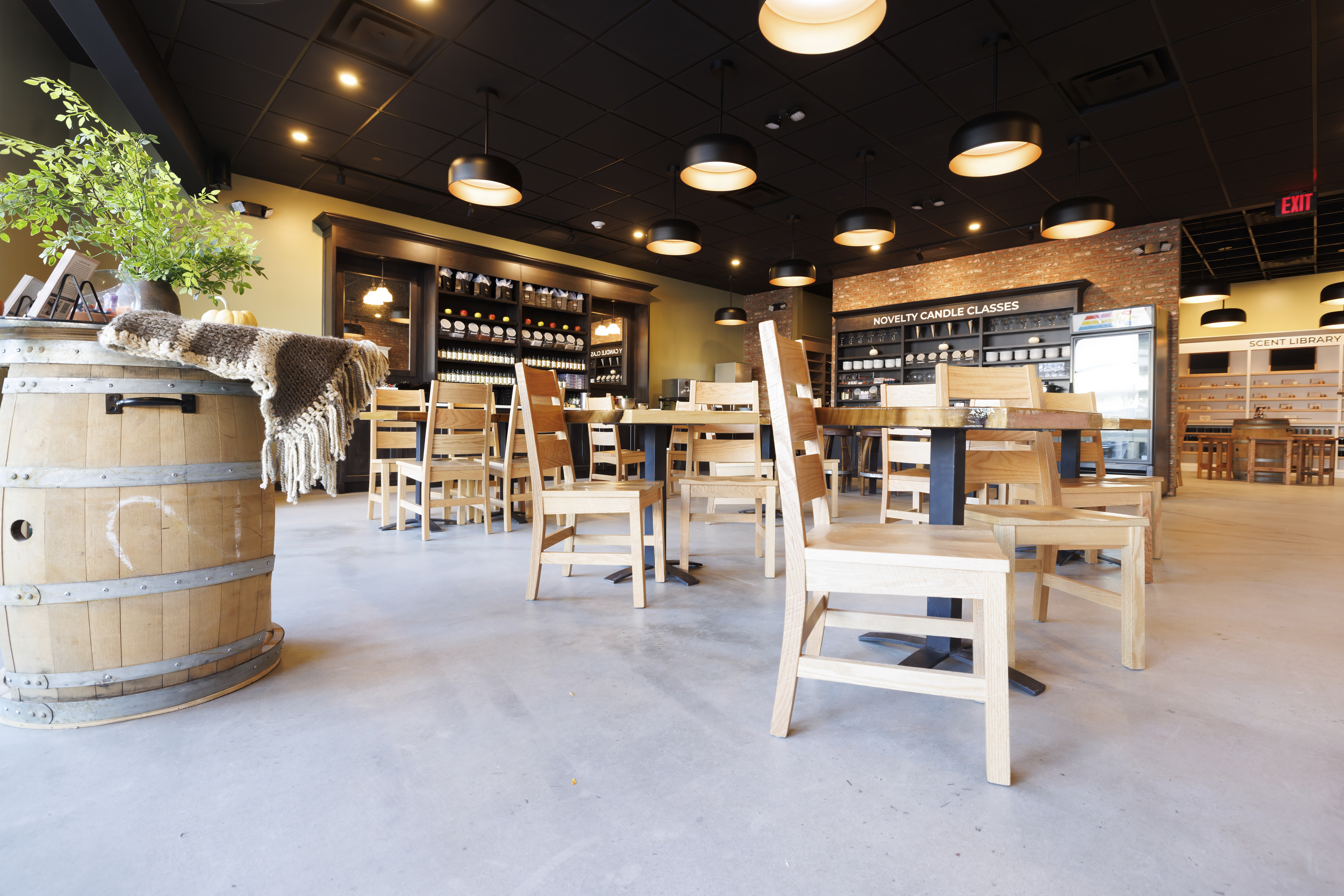 wooden tables and chairs in the foreground and wooden shelves of candles in the background with black ceiling and hanging black lights